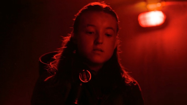 Ellie holding metal pipe under a red light