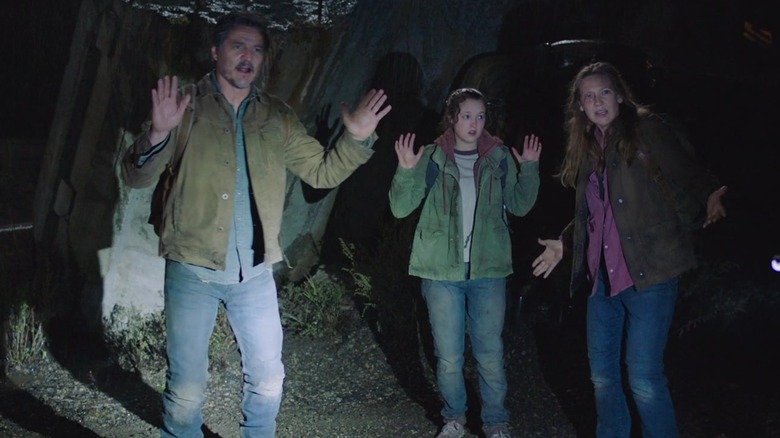 Joel, Ellie, and Tess raising hands in the dark