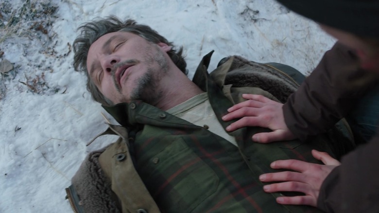 Ellie crouching over injured Joel in the snow