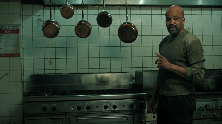 Isaac pointing at cookware in an industrial kitchen