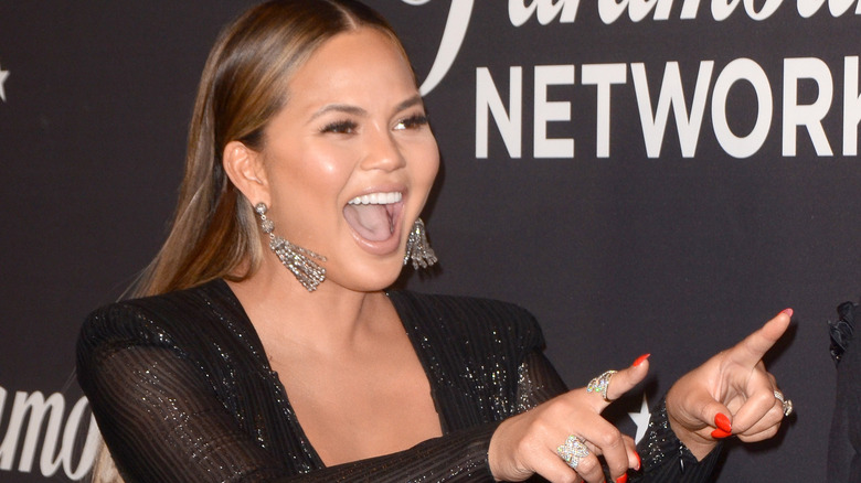 Chrissy Teigen smiling and pointing