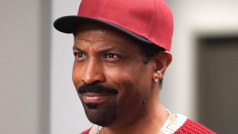 Deon Cole smiling with red baseball cap