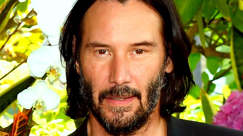 Keanu Reeves in front of flowers