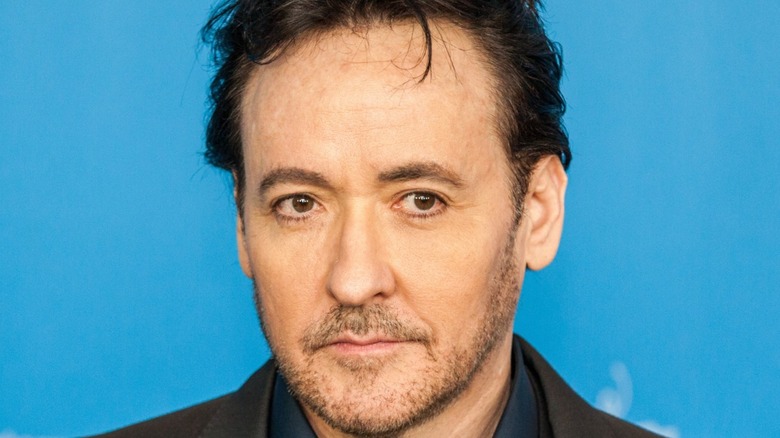 John Cusack smiles with stubble