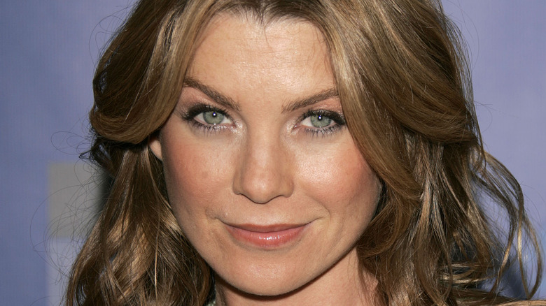 Ellen Pompeo smirks on purple background