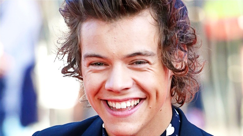 Harry Styles with curly hair smiling