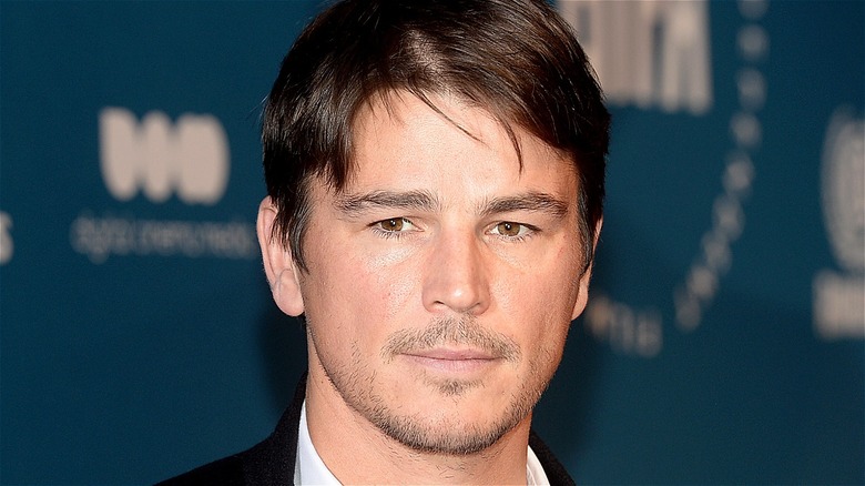 Josh Hartnett stands in front of blue background