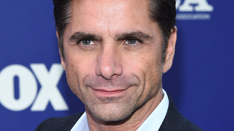 John Stamos smirks at an event