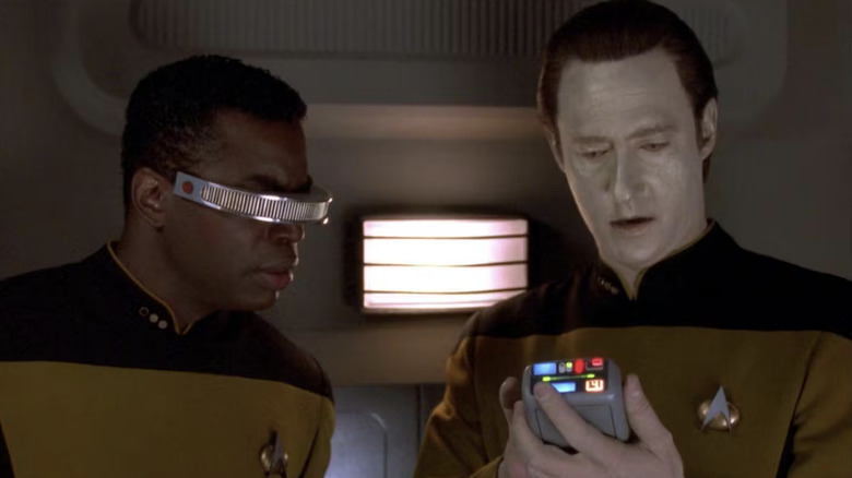 Geordi and Data examine readings on a tricorder in 