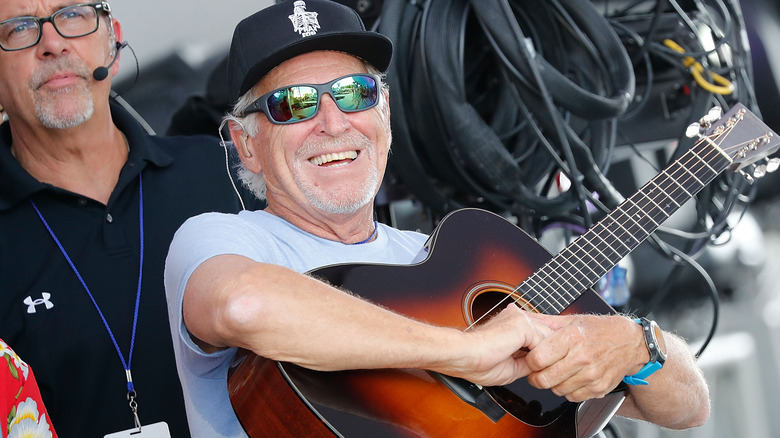 Jimmy Buffett holding a guitar onstage