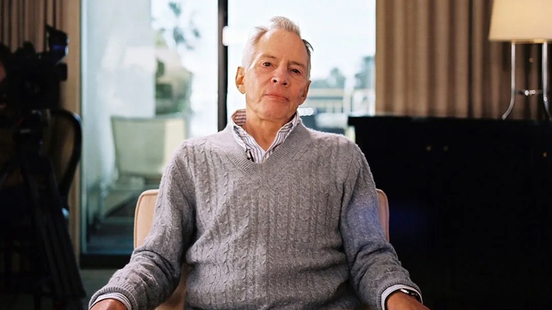 Robert Durst sitting grey sweater