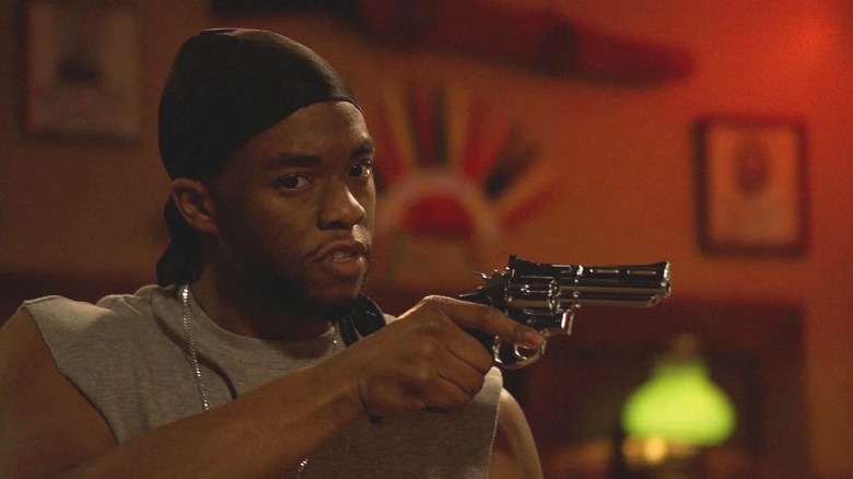 Chadwick Boseman holding a gun
