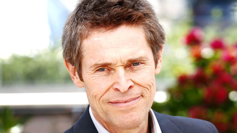 Willem Dafoe smiling outside