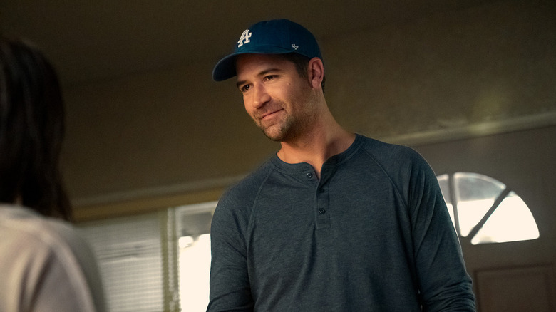 Haller stands in front of a door wearing a T-shirt and baseball cap in "The Lincoln Lawyer" (2022-present)