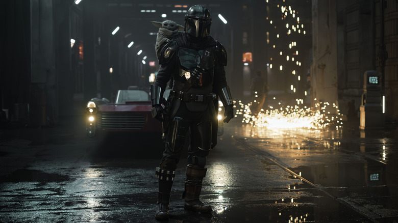 Din Djarin standing in the street with Grogu in The Mandalorian and Grogu