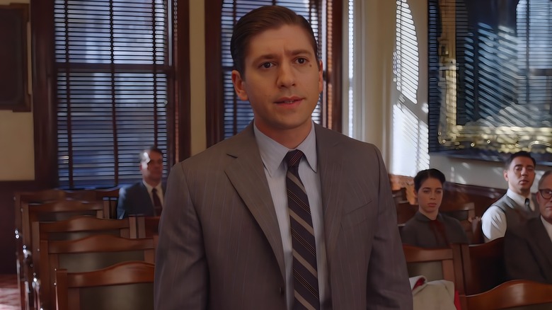 Joel wearing a grey suit in a courtroom