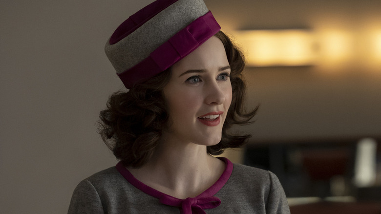 Midge Maisel standing grey hat with maroon bow