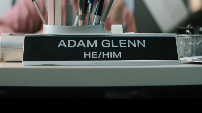 A nameplate reading "Adam Glenn, He/Him" in Masters of the Universe (2026)