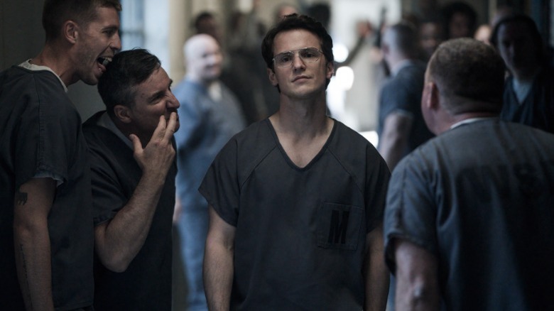 Freddie Stroma walking down hallway of inmates