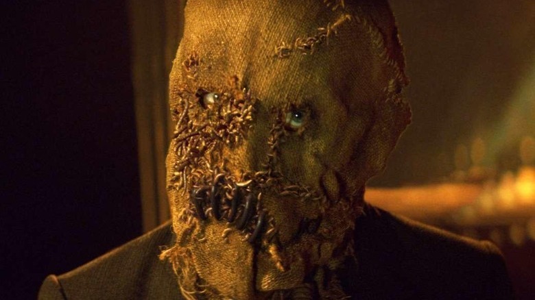 Scarecrow in mask cocks head