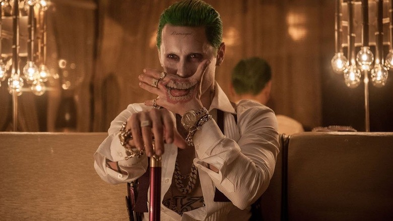 Joker holds a hand with smile tattoo in front of his face in "Suicide Squad" (2016)