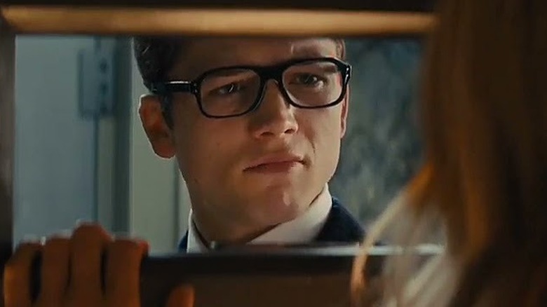 Eggsy looks at Tilde through a door slot in Kingsman: The Secret Service (2014)