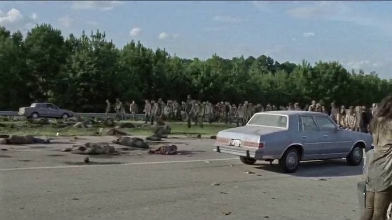 Car drives through crowd of zombies