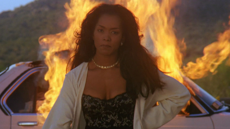 Angela Bassett serious in front of burning car