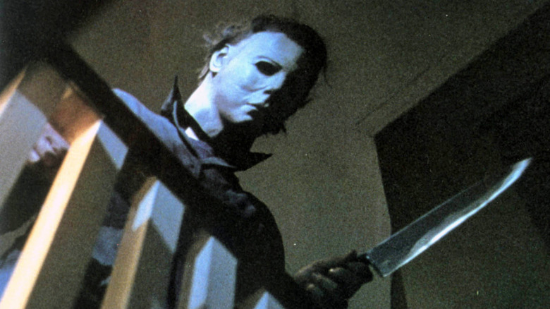 Michael Myers holds knife and looks over stairs
