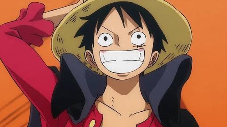 Monkey D. Luffy smiling as he holds his straw hat in One Piece