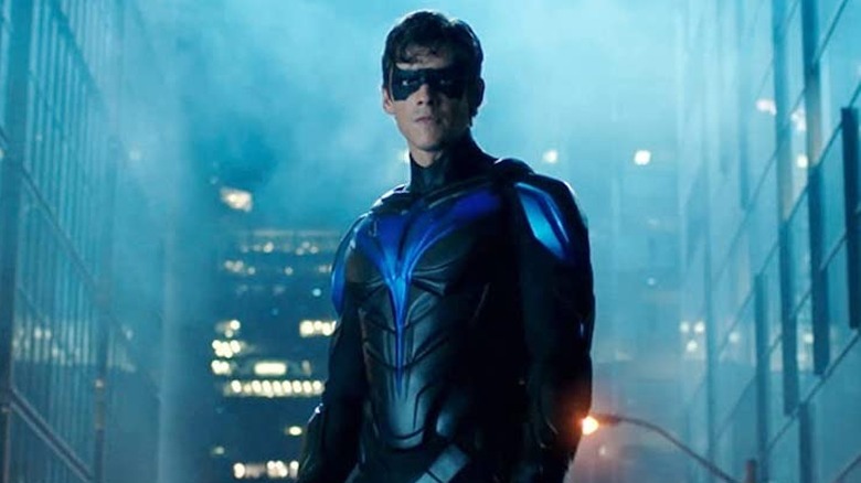 Nightwing standing on a car