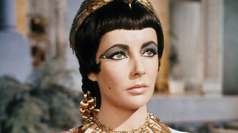 Cleopatra looking up while wearing gold necklace in 