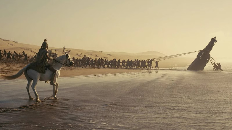 Men pulling the Trojan Horse statue off the beach in The Odyssey (2026)