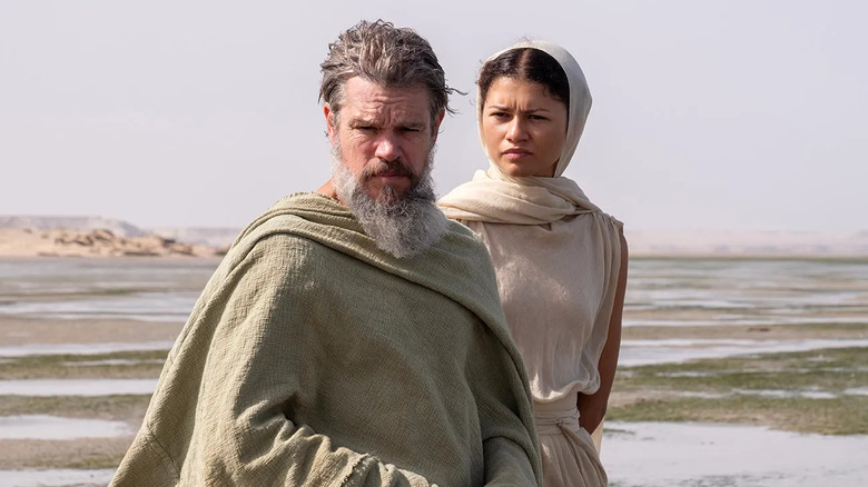 Odysseus standing with Athena on the beach behind him in The Odyssey
