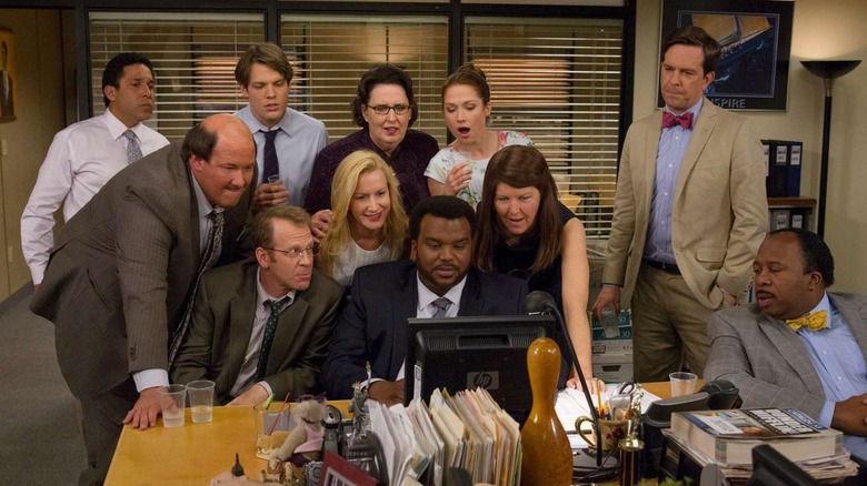 The employees of Dunder Mifflin gather around a monitor