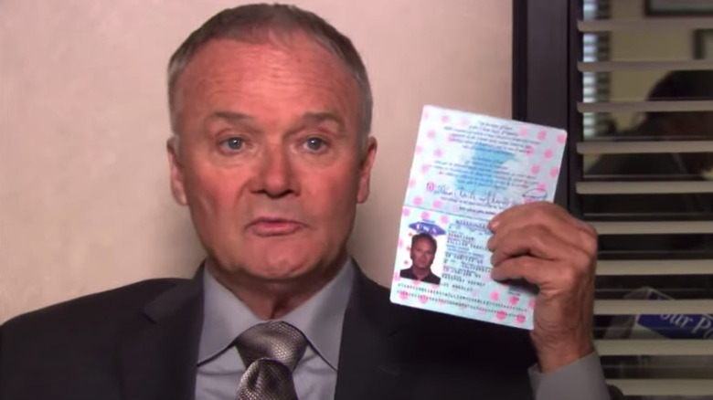 Creed holding up William Charles Schneider passport