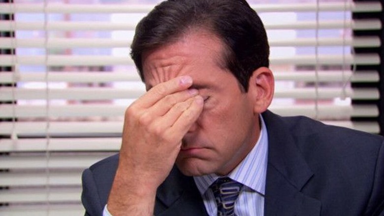 Michael Scott holding the bridge of his nose