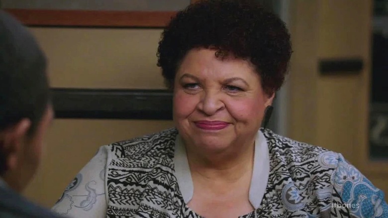Caroline smiles sitting at a table in Bones