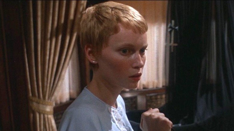 Rosemary holds a knife and slowly walks through her apartment.