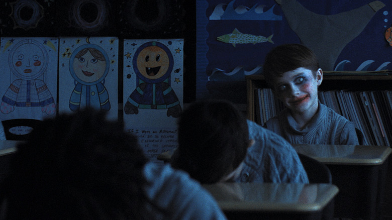 A spectral child leers from the back of class in 