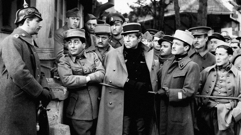 Enemy soldiers surrounding a captive prisoner in Grand Illusion (1937)