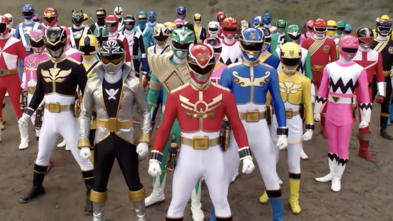 Several generations of Power Rangers stand