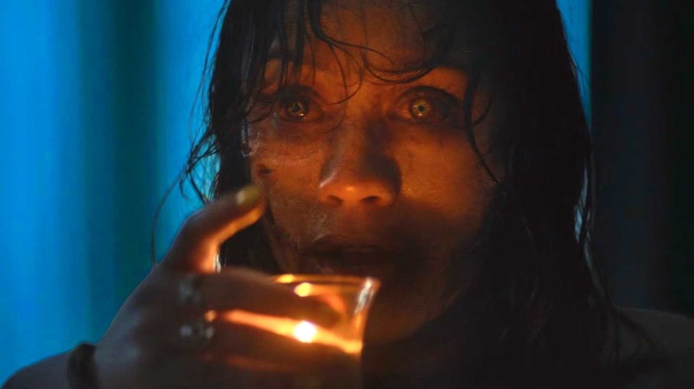 Deadite Thya preparing to drink hot candle wax in "Evil Dead Burn" (2026)