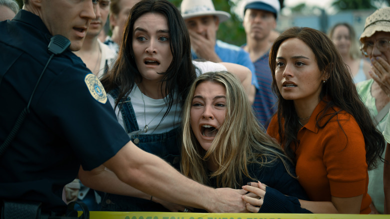 Stevie, Danica, and Ava looking scared behind police tape in 