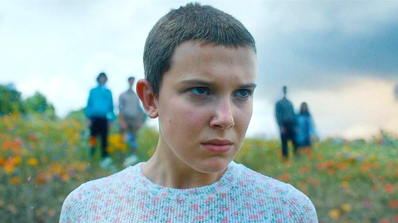 Eleven standing on some grass with her friends behind her in 