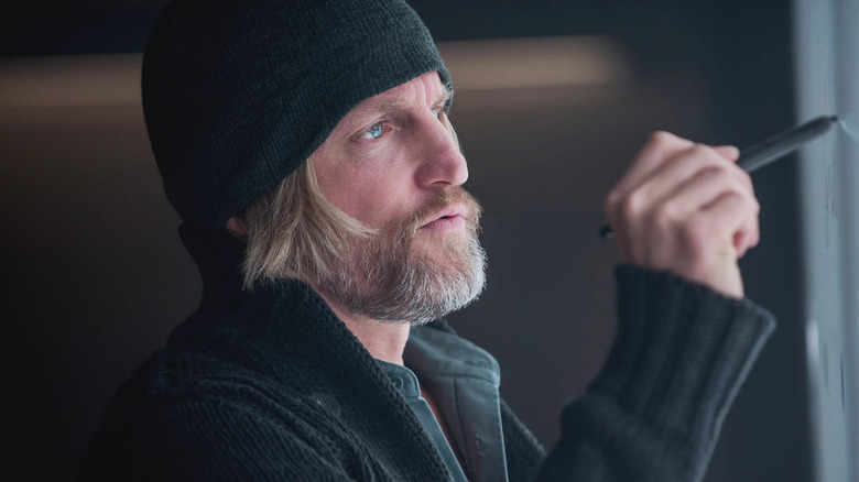 Haymitch writing on a whiteboard wearing a cap in The Hunger Games: Mockingjay Part 1