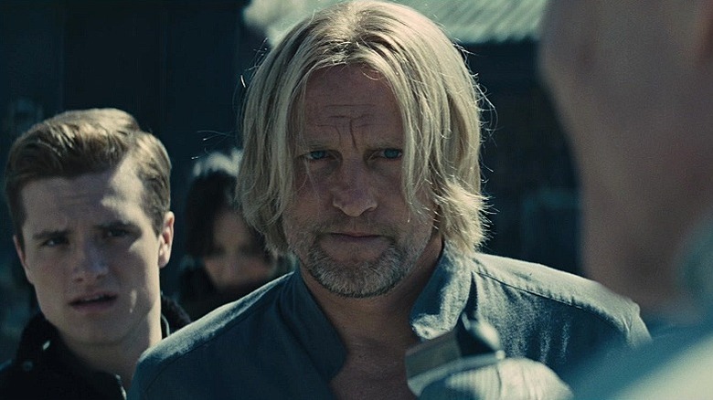 Haymitch standing protectively in front of Katniss and Peeta in The Hunger Games: Catching Fire
