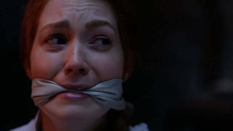 Woman looking terrified with mouth gag