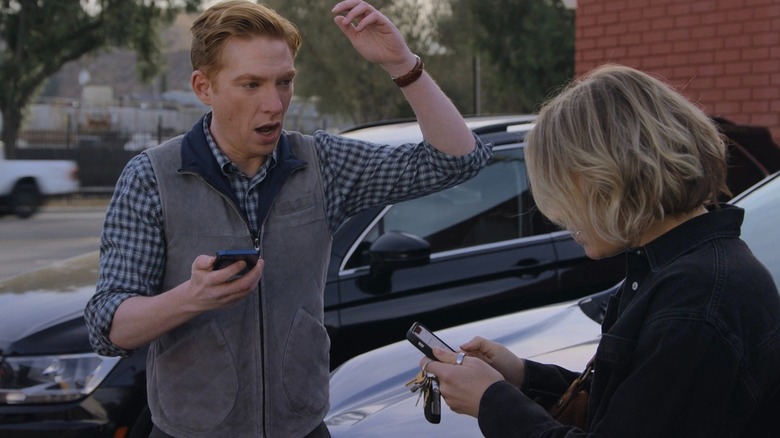 Ned and Mare standing in a parking lot as they find out that the Truth Teller has been nominated for several awards