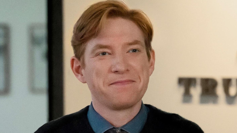 Editor-in-chief Ned Sampson (Domhnall Gleeson) standing in front of a wall sign that reads 